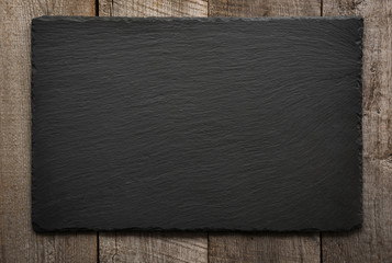black slate tile on wooden background. top view.