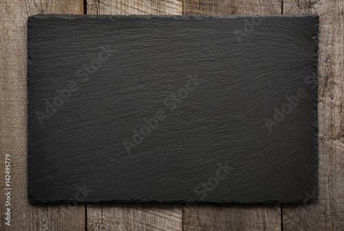 Fotografie, Obraz Black slate tile on wooden background. Top view.