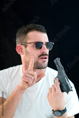 Handsome guy with t-shirt and sunglasses holding a handgun Poster