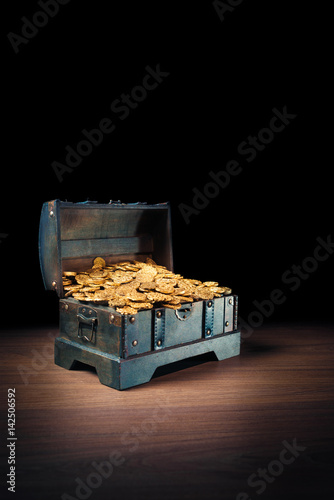 Open treasure chest with gold coins on a dark background