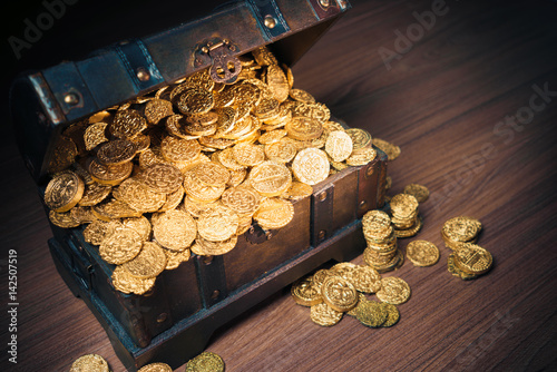 Open treasure chest with gold coins on a dark background