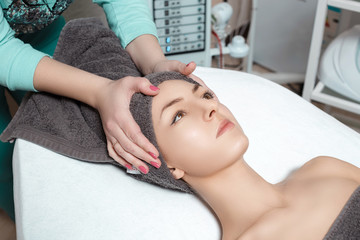 beautician prepares patient for Spa procedures in Spa salon. young woman with towel on head