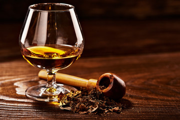 Wall Mural - Glass of cognac and pipe with tobacco on wooden table