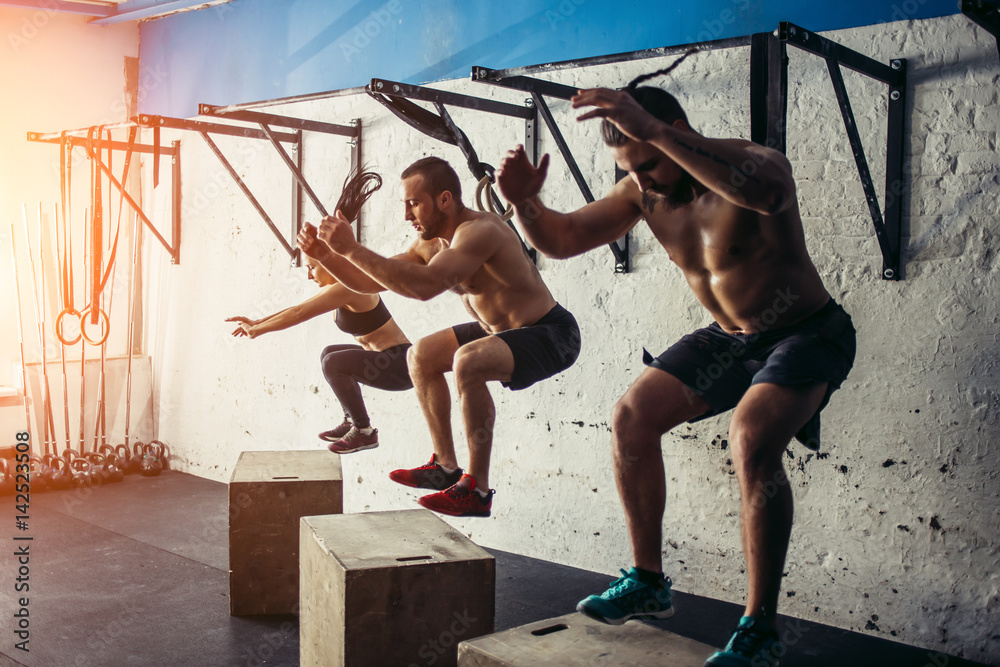 Group of man and woman jumping on fit box at gym - obrazy, fototapety, plakaty 