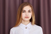 Office Girl In A White Blouse Against A Background Of Brown Curtains