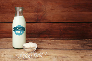 Canvas Print - Bottle of milk and little bowl with rice on wooden background