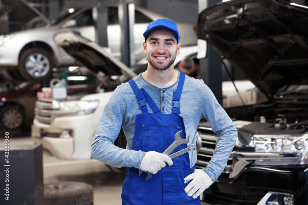 Young mechanic standing in front of open car hood