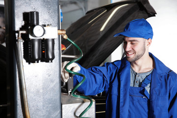 Wall Mural - Young mechanic standing near auto lift in car service