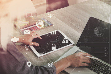 Poster - businessman working with laptop computer and digital tablet and book and document on wooden desk in modern office with virtual icons interface