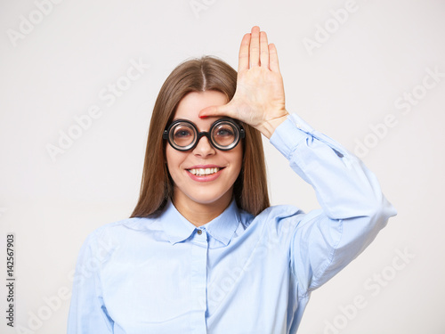 Fotografie, Obraz Studio portrait of funny happy young business woman in nerd eyeglasses isolated on gray