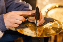 Craftsman Hands With Hammer Working On A Golden Plate