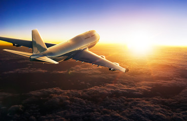 Wall Mural - airplane flying above clouds during sunset