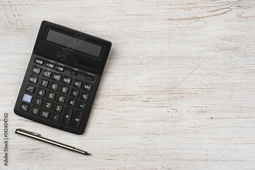 Fotomural Ink pen and black calculator isolated on wooden texture background