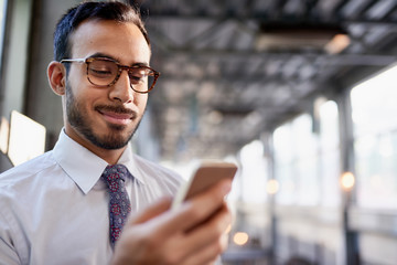 Indian businessman smiling confidently and surfing the net on a smartphone