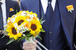 Bouquet sposi  fatto di girasolitenuto dallo sposo. Sullo sfondo un altro invitato.