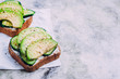 Healthy toast with cottage cheese, green cucumber and avocado on wooden board on a marble gray table background. Horizontal image, top view top, copy space. Vegetarian food content