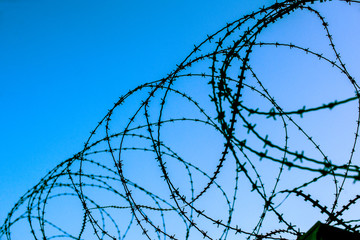 Top of fortress concrete security wall topped with barbed wire against blue sky background - view from prison and  freedom concept 