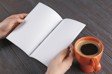 Sticker - Female hands holding blank brochure on wooden background