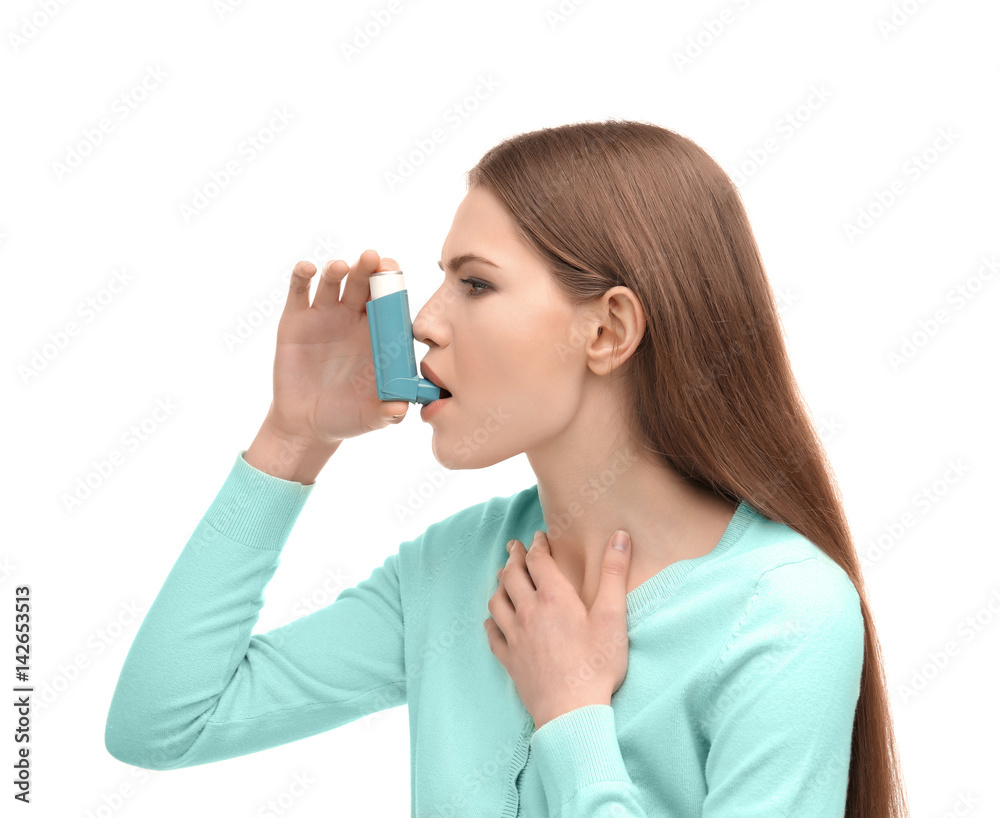 Young woman using asthma inhaler on white background
