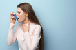© Africa Studio - Young woman using asthma inhaler on color background