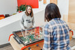 © EdNurg - Two happy women friends playing table football at leisure time
