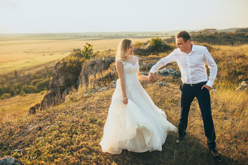 Wall Mural - wedding couple running and having fun in mountains in sunset light