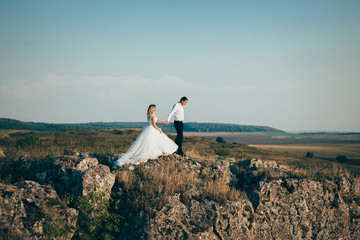 Wall Mural - stylish gorgeous couple newlyweds standing on the rocks in the mountains