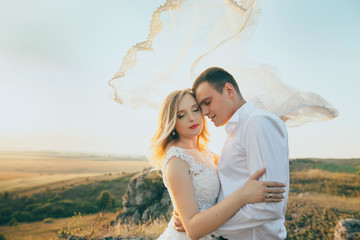 Wall Mural - wedding couple covered with bridal vail at sunset