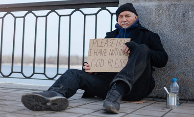 Jobless elderly man sitting on the cardboard box