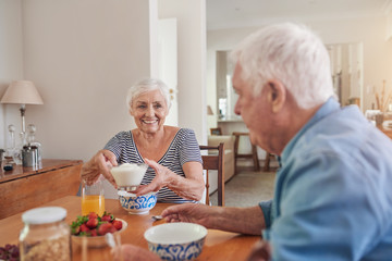 Content seniors eating a healthy breakfast together at home