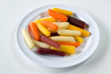 Rainbow baby carrots against white background- healthy food eating concept