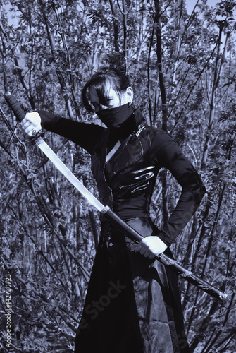 Zdjęcie XXL Ninja w masce odsłania katanę przed walką. Czarno-białe zdjęcie