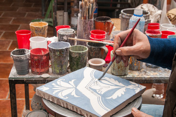 Wall Mural - Pottery artisan in Caltagirone, Sicily, decorating just enamelled square tiles in his work table