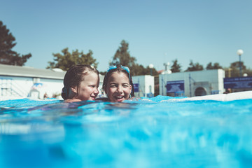 Underwater fun. Two cute little girls with goggles swimming underwater and diving in the swimming poll. Kids sport and leisure.