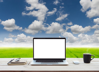Poster - laptop computer showing white screen on work table meadow and blue sky view background