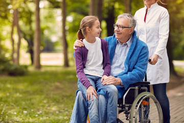 Wall Mural - Senior man on wheelchair with his granddaughter.