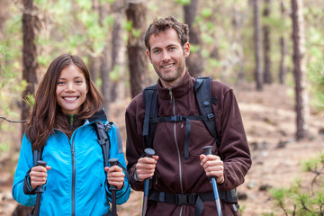 Wall Mural - Happy young multiracial people hiking outdoors in nature forest. Healthy couple multiethnic group. Smiling Asian woman and Caucasian man in autumn.