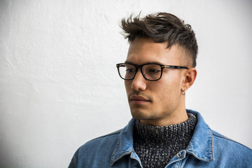 Wall Mural - Handsome white asian young man wearing blue denim jacket, standing on light background against wall in studio shot