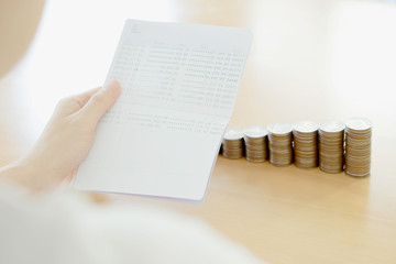 Woman hold passbook on hand, coins background