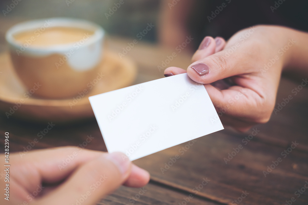 Business man giving  business card to business woman with coffee cup on wooden table background - obrazy, fototapety, plakaty 