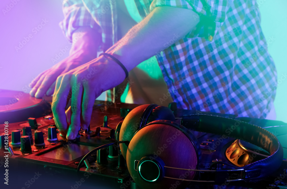 DJ mixing tracks on a mixer in a nightclub