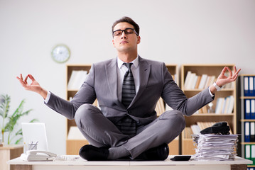 Young businessman meditating in the office