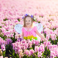 Little girl in fairy costume playing in flower field