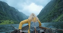 Strong Woman rowing boat in stormy weather on Fjord Norway scenic landscape nature background view enjoying vacation travel adventure