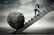 Female entrepreneur carrying big stone on the stair