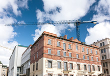 Old Brick Building Under Reconstruction With Tower Crane On Blue Sky Background