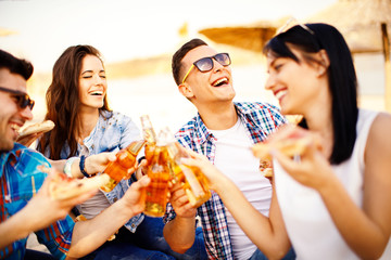 Wall Mural - Happy people drink beer and eating pizza on the beach