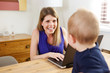 © mimagephotos - cheerful woman working on laptop and looking at baby son