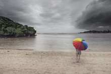 A Lady And Colorful Umbrella At The Beach With Stormy Sky
