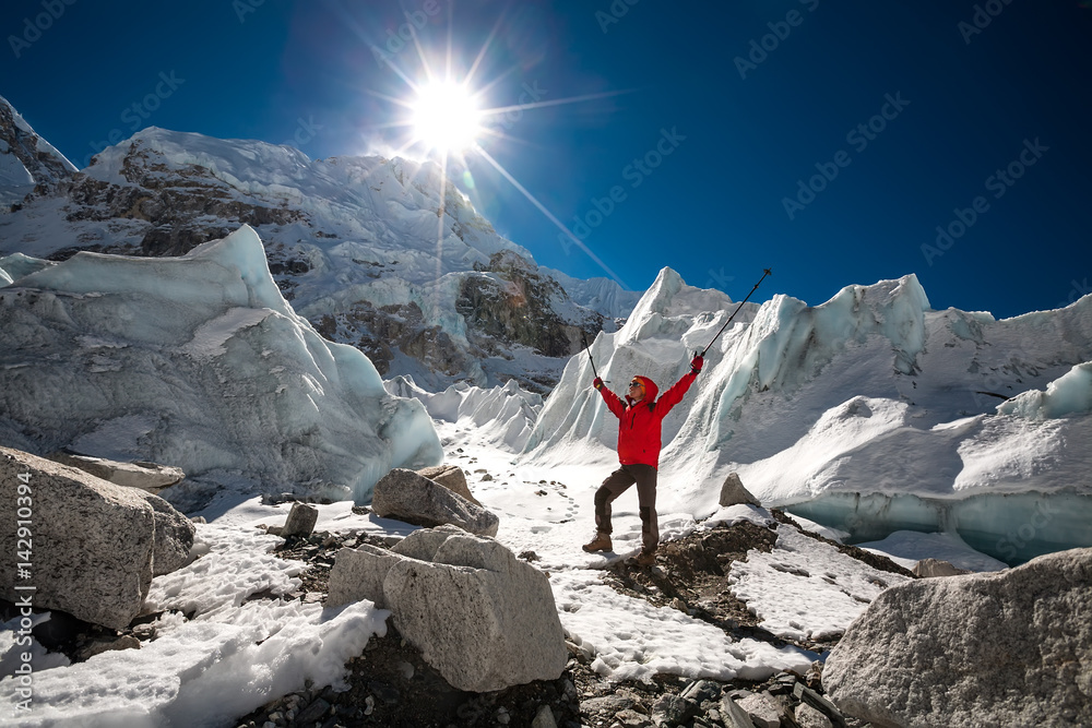 Trekkes is posing at camera in front of huge glacier falling from ...